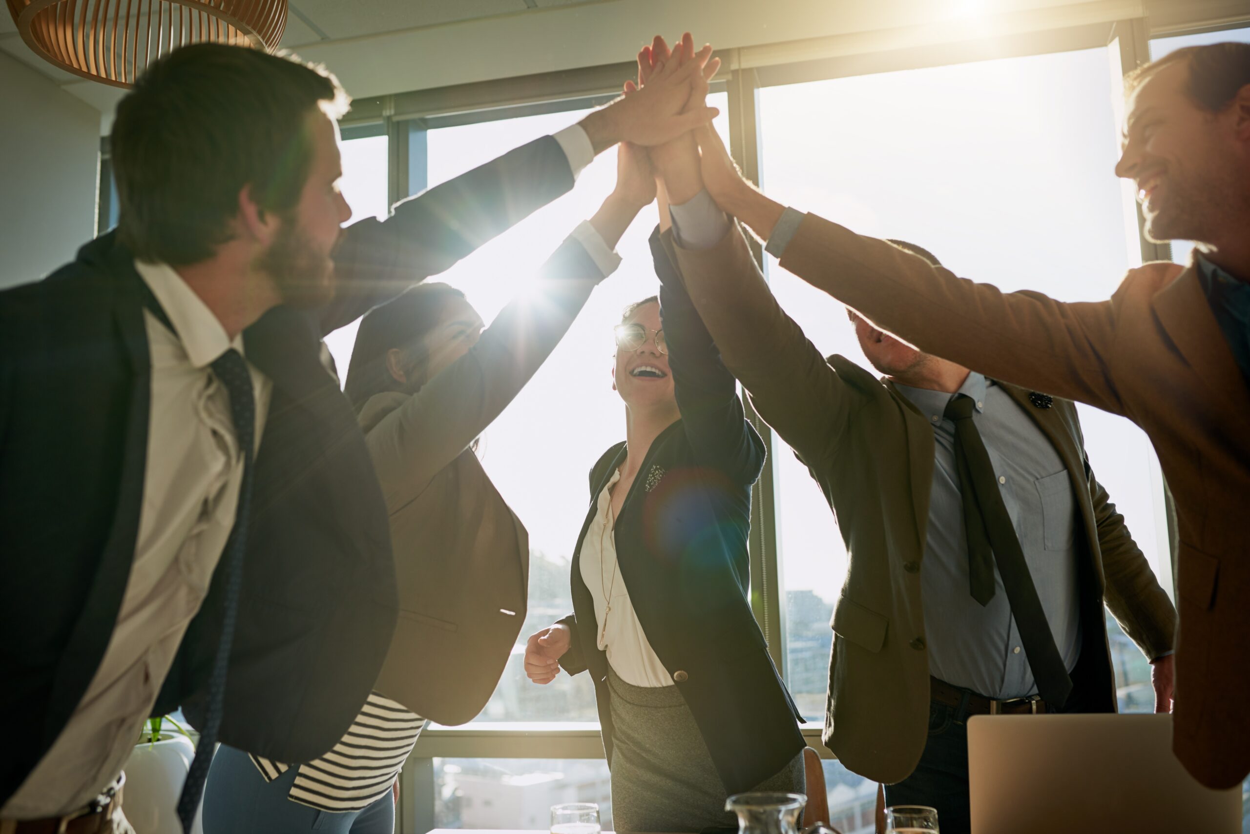 A group of business professionals celebrating team success with a high-five.